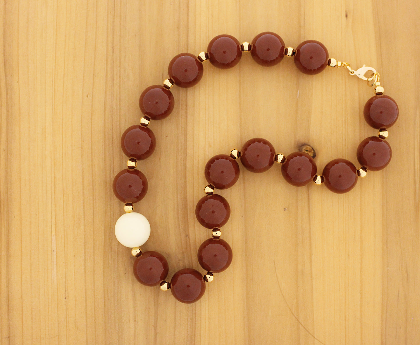 Brown bubble gum necklace with gold and one white off bead.